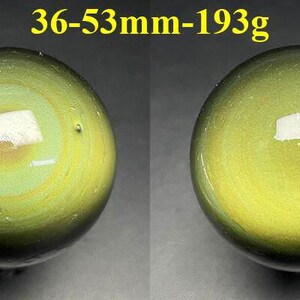 May include: Two polished, spherical gemstones with a swirling pattern of green and yellow hues. The text above the spheres reads "36-53mm-193g". The spheres have a reflective surface.