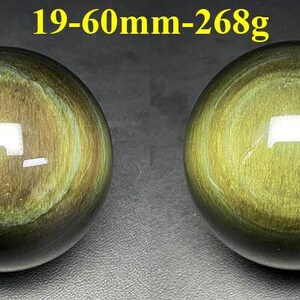 May include: Two polished, spherical gemstones with a golden-green iridescence. The spheres have concentric patterns and a glossy finish. Text at the top reads "19-60mm-268g". These decorative spheres could be used as paperweights or display pieces.