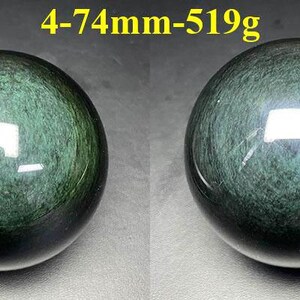 May include: Two polished, dark green obsidian spheres. The spheres have a reflective surface and a swirling pattern. The text "4-74mm-519g" is in the upper center. Each sphere is approximately 2.9 inches in diameter and weighs 1.14 pounds.