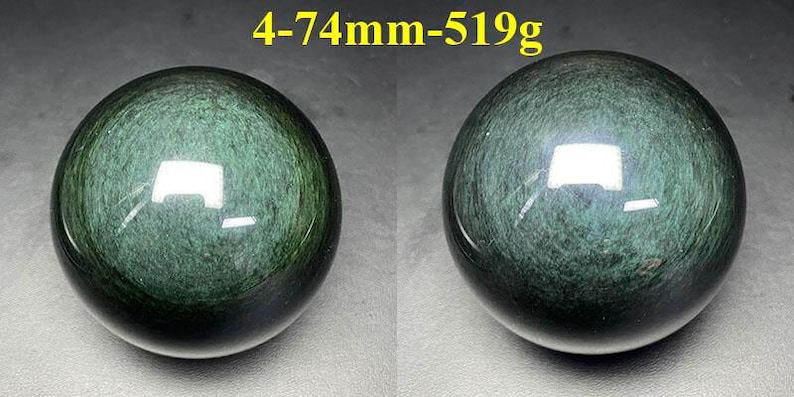 May include: Two polished, dark green obsidian spheres. The spheres have a reflective surface and a swirling pattern. The text "4-74mm-519g" is in the upper center. Each sphere is approximately 2.9 inches in diameter and weighs 1.14 pounds.