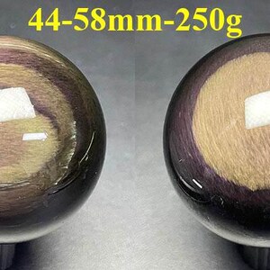 May include: Two polished obsidian spheres, each with a swirling pattern of gold, purple, and black. The spheres are approximately 1.7 to 2.3 inches in diameter and weigh 8.8 ounces. The text "44-58mm-250g" is visible above the spheres.