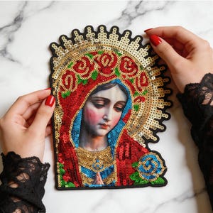 May include: A decorative embroidered patch featuring a detailed portrait of the Virgin Mary. The design is embellished with vibrant red, blue, and gold sequins, showcasing a halo, floral patterns, and a blue rose accent on a black fabric base.