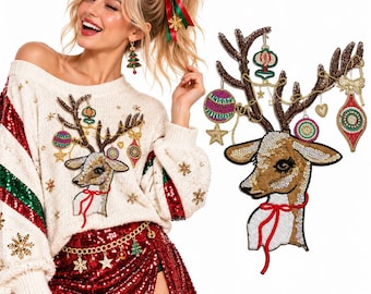 Puede incluir: Un suéter de punto color crema con una cabeza de reno de lentejuelas, cuyas astas están decoradas con adornos colgantes, estrellas y una cinta roja. Las mangas tienen rayas de lentejuelas rojas y verdes y copos dorados, junto a una falda de lentejuelas roja.