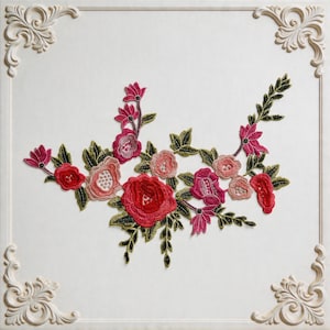 May include: Embroidered floral design featuring red, pink, and peach-colored roses and other flowers with green leaves. The design is set against a white background with decorative corner accents, creating a classic and elegant aesthetic.