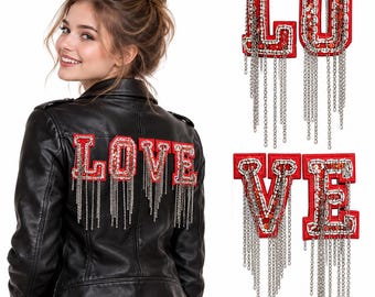 Puede incluir: Una chaqueta de cuero negro con cuatro parches de letras rojas individuales que forman la palabra LOVE. Cada letra está adornada con lentejuelas y cuentas plateadas, y presenta largas cadenas de metal plateado colgando de la base.