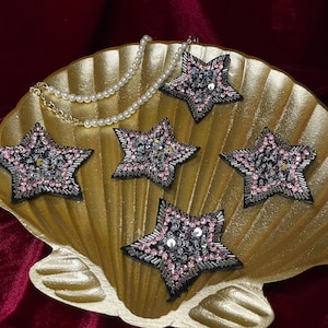 Puede incluir: Una taza de cerámica blanca con un asa negra y el texto "But First, Coffee" en negrita negra. La taza se encuentra sobre un fondo borroso, sugiriendo un ambiente acogedor.