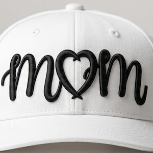 以下が含まれることがあります： 白い野球帽。 黒い筆記体で「mom」の文字が刺繍されています。「mom」の「o」はハート型に置き換えられています。 キャップはカーブしたつばと上部にボタンが付いています。