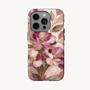 Puede incluir: Funda de teléfono con un diseño floral con flores rosas y blancas, hojas verdes y detalles dorados. La funda tiene un acabado brillante y un recorte para múltiples lentes de cámara.