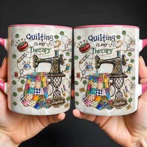 May include: Two white ceramic mugs with pink handles and rims. Each mug features a sewing machine, quilting tools, and the text "Quilting is my Therapy." The mugs are personalized with the name "Sophia."