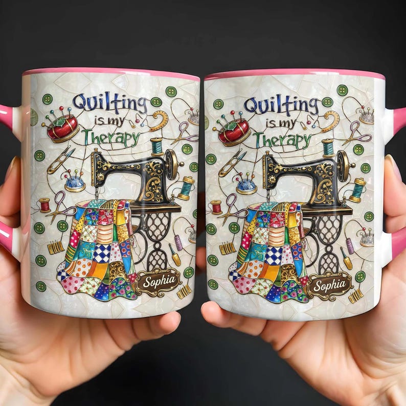 K&ouml;nnte beinhalten: Zwei wei&szlig;e Keramikbecher mit rosa Griffen und R&auml;ndern. Jeder Becher zeigt eine N&auml;hmaschine, Quiltwerkzeuge und den Text "Quilting is my Therapy". Die Becher sind mit dem Namen "Sophia" personalisiert.