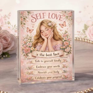 May include: A rectangular acrylic block with an illustration of a woman with blonde hair, flowers, and butterflies. The text "SELF LOVE is the best love" is displayed above the image, with inspirational phrases below, such as "Embrace your worth".