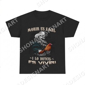 May include: Black t-shirt featuring a skeleton wearing a cowboy hat and holding a rooster. The text "MORIR ES FACIL" is above the skeleton, and "I LO DIFICIL ES VIVIR!" is below. The design is detailed with vibrant colors.