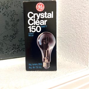 May include: A black rectangular GE Crystal Clear 150 watt light bulb box. The packaging features the GE logo, the text Crystal Clear 150 Watt Light Bulb, and technical specifications including 2850 average lumens and 750 hours average life.