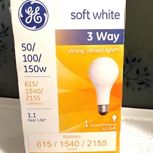 May include: A GE soft white 3-way A21 light bulb box featuring 50/100/150W power, 615/1540/2155 lumens, and a 1.1 year life. The packaging displays the GE logo, bulb image, and energy cost details of $6.02, $12.05, and $18.07 per year.