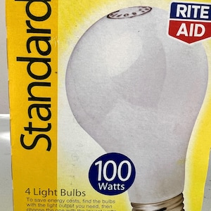 May include: A box of four 100-watt light bulbs. The packaging is yellow with the word "Standard" in black. The light bulb is white with a metal base. The box also features the Rite Aid logo and details on light output and lifespan.