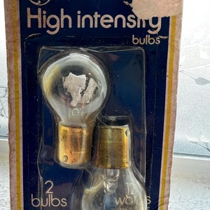 May include: Package of two GE high intensity bulbs. The bulbs are clear with a gold base. The packaging is blue with yellow trim and the text "High intensity bulbs" and "12 watts".
