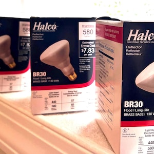 May include: Three Halco BR30 reflector light bulb boxes featuring a white and red design. Each box displays the text Halco, BR30, Flood | Long Life, Brass Base, 130 Volts, 580 lumens, and an estimated energy cost of $7.83 per year on the front.