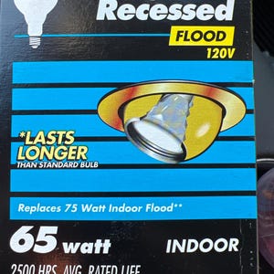 May include: A Philips Longer Life Recessed Flood 65-watt light bulb in a box. The box is black with blue and yellow accents. Text on the box includes "Lasts Longer Than Standard Bulb" and "Replaces 75 Watt Indoor Flood". The bulb has a 3 3/4" diameter.