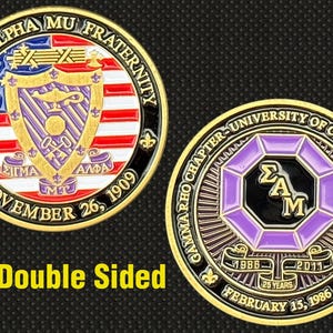 May include: Double-sided Sigma Alpha Mu fraternity coin. One side features the fraternity crest with red, white, and blue accents, and the text "November 26, 1909." The other side displays the Gamma Rho chapter seal, with the text "University of California San Diego."