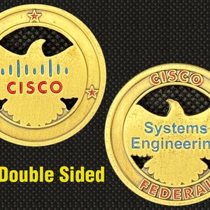 May include: Two-sided gold-colored coin with the word "CISCO" in red and blue, and an eagle design. The coin also features the text "Systems Engineering" and "FEDERAL". The words "Double Sided" are also visible.
