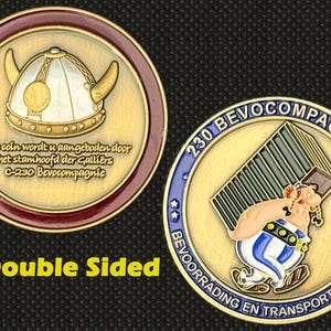 Puede incluir: Moneda dorada de doble cara con un diseño de casco vikingo en una cara y un personaje de dibujos animados con un barril en la otra. La moneda tiene texto en holandés e inglés.