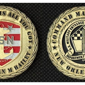 Può includere: Moneta commemorativa color oro con la scritta "ALL IT TAKES IS ALL YOU GOT" e "CMOCM SEAN M BAILEY". La moneta presenta la bandiera americana, un'ancora e le lettere "USN". Il retro recita "COMMAND MASTER CHIEF" e "NEW ORLEANS MEPS".