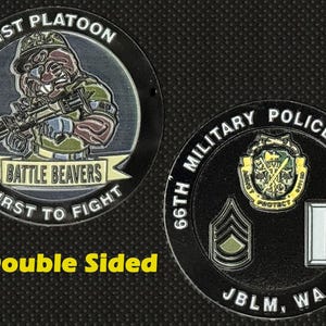 May include: Double-sided military coin. One side features a soldier with a weapon, the text "1st Platoon", "Battle Beavers", and "First to Fight". The other side displays military insignia and "66th Military Police Company".