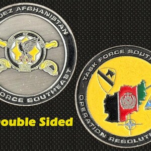 Può includere: Moneta a doppia faccia con la scritta "GARDEZ AFGHANISTAN TASK FORCE SOUTHEAST" su un lato e una mappa dell'Afghanistan sull'altro. La moneta presenta una combinazione di colori argento e giallo con insegne militari.