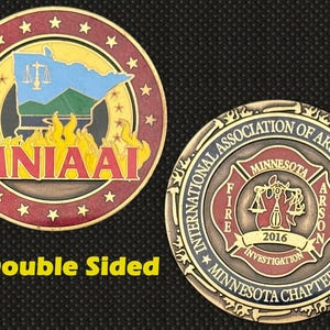 May include: Double-sided coin featuring the Minnesota state outline, scales of justice, and flames. The coin's reverse side displays the International Association of Arson Investigators logo and text. The coin is bronze with red, yellow, and blue accents.