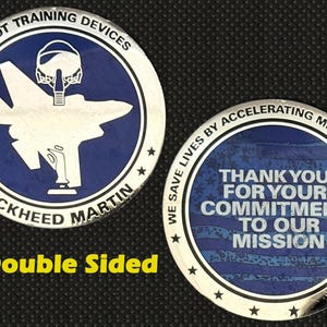 Może przedstawiać: Dwustronna moneta z niebieskim i srebrnym wzorem. Jedna strona przedstawia sylwetkę samolotu oraz tekst "Pilot Training Devices" i "Lockheed Martin". Druga strona mówi "Thank You For Your Commitment To Our Mission."