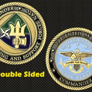 Puede incluir: Moneda dorada de doble cara con diseños detallados. Un lado presenta un emblema de tridente y estrella, el otro un águila con el texto "Power for Peace". El texto incluye "Commander" y "Striking and Support Forces NATO".