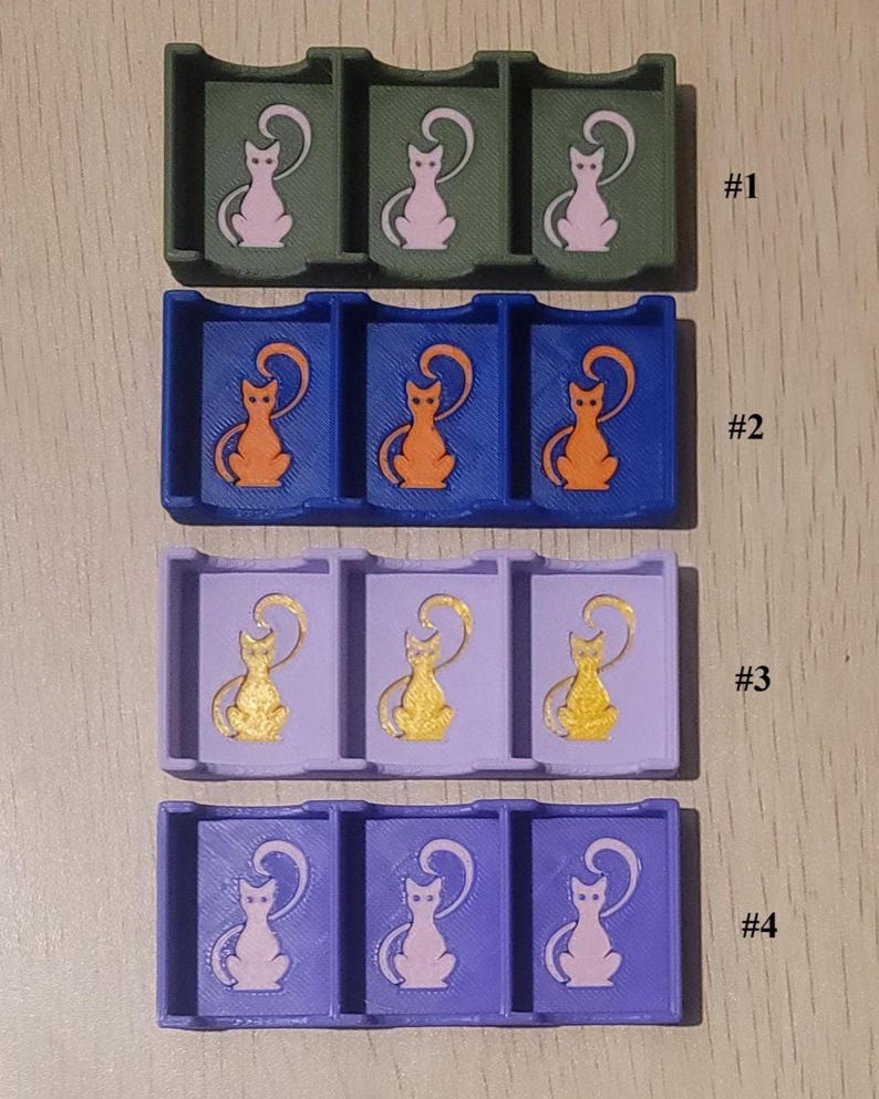 May include: Four rectangular plastic organizers, each featuring three compartments with a cat silhouette graphic. Row #1 is olive green with pink cats, #2 is blue with orange cats, #3 is light purple with gold cats, and #4 is purple with pink cats.