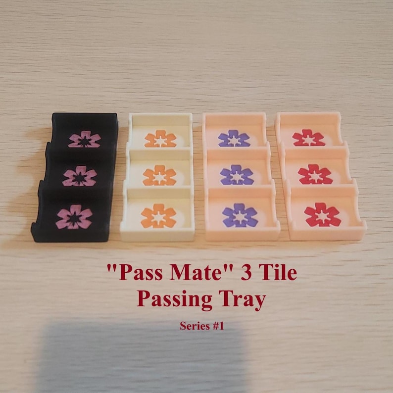May include: Four "Pass Mate" 3 Tile Passing Trays in black, cream, light pink, and light pink. Each tray has three tiers with a floral design. The text "Pass Mate" 3 Tile Passing Tray Series #1" is below the trays.