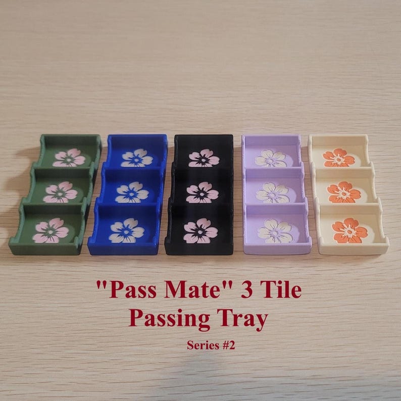 May include: A set of five colorful "Pass Mate" 3 Tile Passing Trays, each with a floral design. The trays are in shades of green, blue, black, lavender, and cream. The text "Pass Mate" 3 Tile Passing Tray Series #2" is printed below the trays.