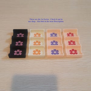 May include: Four rectangular organizers with three compartments each, featuring a six-petaled flower icon in each section. Colors include black, white, light peach, and pale pink. Text reads: These are the 1st Series. Check it out in our shop.