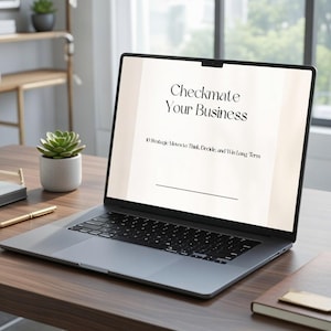 May include: A silver laptop displaying the text "Checkmate Your Business" on a light background. The laptop sits on a dark wooden desk, next to a succulent in a white pot, a pen, and a notebook.