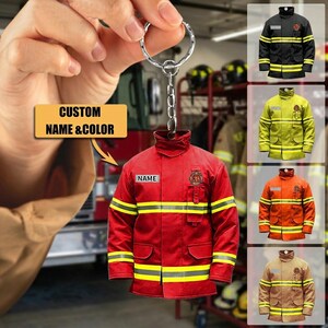 May include: A red firefighter jacket keychain with yellow reflective stripes and the word "NAME" on a patch. The keychain has a silver ring and chain. The image also shows examples of the jacket in black, yellow, orange, and tan.