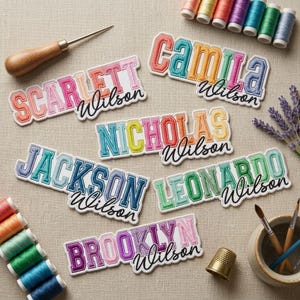 May include: Six embroidered name patches featuring the names Scarlett, Camila, Nicholas, Jackson, Leonardo, and Brooklyn, each paired with the surname Wilson in script. Includes a wooden awl, a gold thimble, and colorful thread spools.