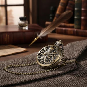 Op de afbeelding: Antieke bronzen zakhorloge met een octopusontwerp op de wijzerplaat. Het horloge, met zijn ketting, staat tegen een achtergrond van boeken, een ganzenveer en een textuurstof.