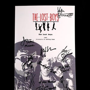 Könnte beinhalten: Ein Filmplakat für "The Lost Boys" mit dem Titel in Rot und Schwarz. Das Plakat zeigt Silhouetten von Personen, die am Titel hängen, und die Gesichter der Schauspieler. Das Plakat ist von mehreren Personen signiert.