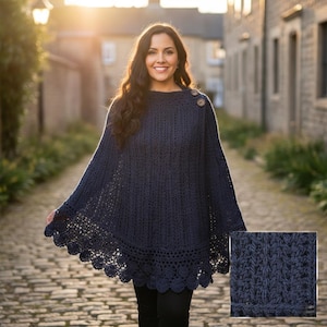 Op de afbeelding: Een marineblauwe gehaakte poncho met een geschulpte rand en twee houten knopen. De poncho heeft een textuurgebreid patroon en wordt over zwarte kleding gedragen. De afbeelding bevat een close-up van het gebreide patroon.