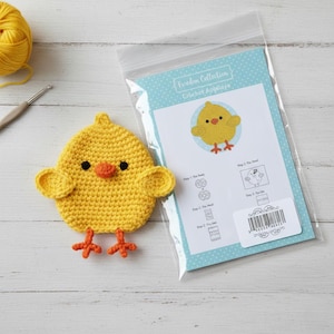 May include: A handmade yellow crochet chick with orange feet, beak, and black eyes. The chick is next to a package labeled "Freedom Collection Crochet Applique" with a matching chick illustration and instructions.