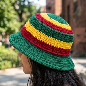 May include: A handmade crochet bucket hat in green, red, and yellow. The hat has a wide brim and is striped with bands of green, red, and yellow. The hat's design is reminiscent of the Rastafarian flag.