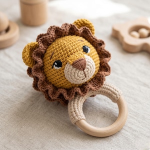Può includere: Un sonaglio a forma di leone all'uncinetto fatto a mano con un anello di legno. Il leone ha una testa gialla, una criniera marrone e un muso beige. Il sonaglio è progettato per neonati e bambini piccoli.