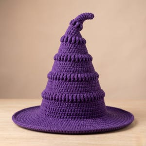 Peut inclure: Un chapeau de sorcière violet crocheté à la main, avec un large bord et un sommet pointu et incurvé. Le chapeau présente un design à plusieurs niveaux avec des détails texturés, parfait pour Halloween ou les soirées costumées.