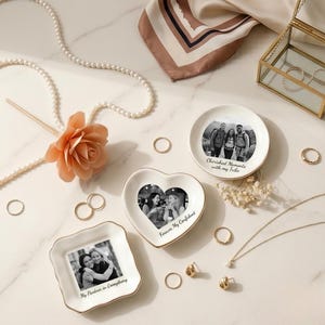 Op de afbeelding: Drie witte keramische schaaltjes met gouden randen, elk voorzien van een zwart-witfoto en tekst. Het ronde schaaltje draagt de tekst Cherished Moments with my Tribe, het hartvormige schaaltje Forever My Confidant en het vierkante schaaltje My Partner in Everything.