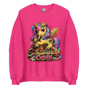 Könnte beinhalten: Ein pinkfarbenes Sweatshirt mit einem Cartoon-Einhorn-Design. Das Einhorn hat einen goldenen Körper, eine bunte Mähne und Flügel. Es sitzt auf einem Haufen Süßigkeiten und Schokolade, mit dem Text "Powered by Candy".