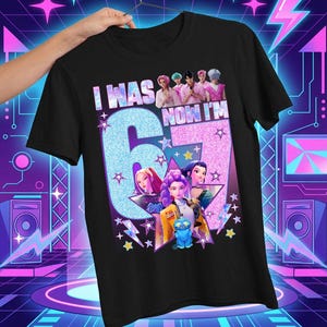 May include: Black t-shirt with the text "I WAS 6 NOW I'M 7" in a glittery design. The shirt features a colorful graphic of animated characters and stars, perfect for a birthday celebration.