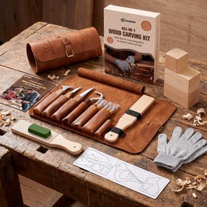 May include: A wood carving kit featuring a brown leather tool roll, several carving knives with wooden handles, a sharpening strop with a green compound, a pair of gray safety gloves, wooden blocks, an instruction manual, and a pattern sheet.