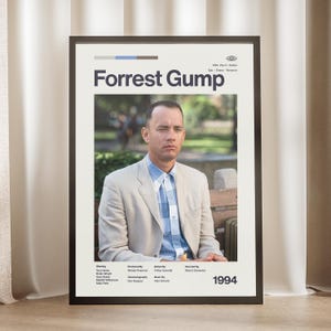 May include: Framed movie poster for "Forrest Gump" featuring Tom Hanks. The poster has a beige background with the movie title in large white letters. The image shows Tom Hanks in a light-colored suit and blue plaid shirt. The year 1994 is at the bottom.